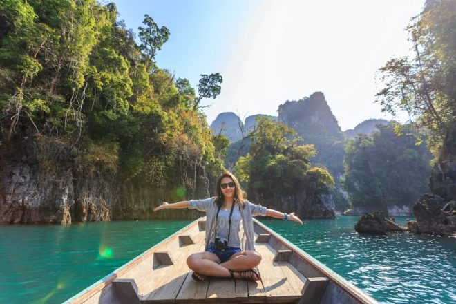 photo of woman sitting on boat spreading her arms
